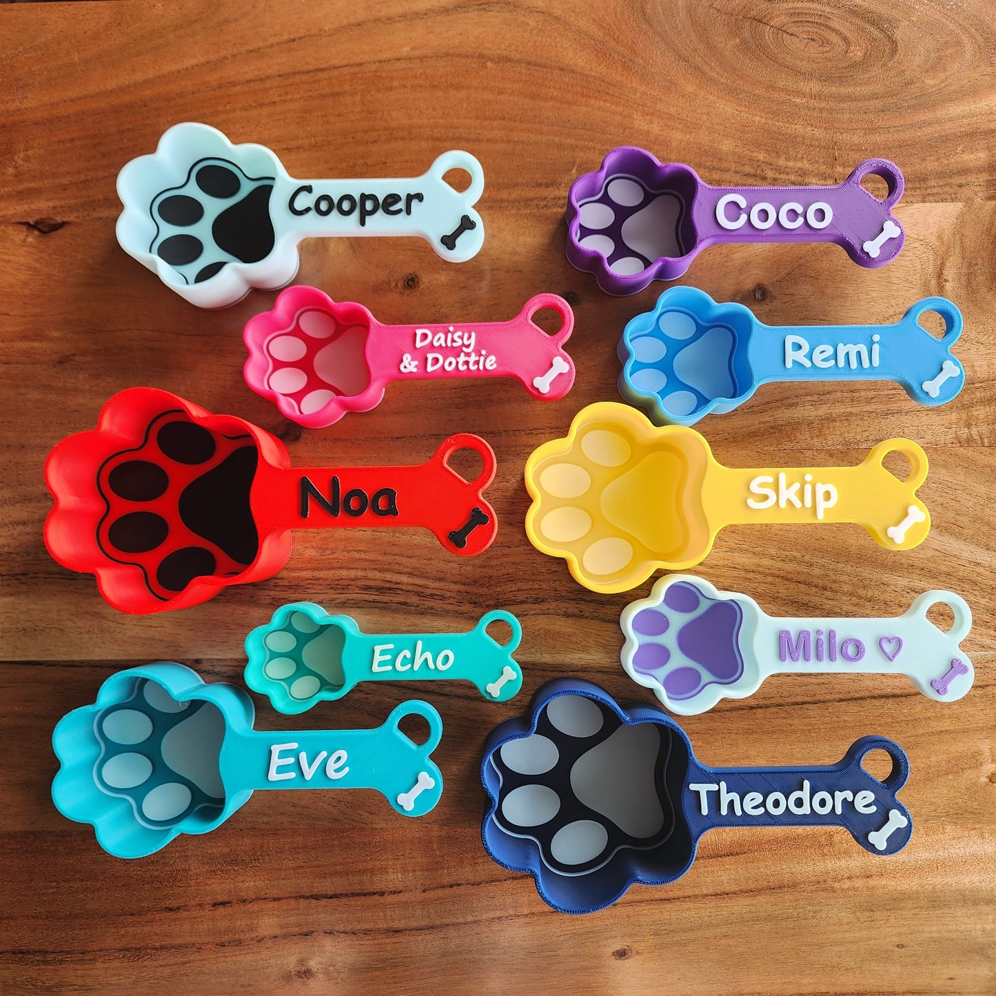 Multiple dog food scoops, baby blue with black, pink with white, red with black, mint with vanilla, teal with white, purple with white, light blue with baby blue, yellow with white, baby blue with violet, navy with white.